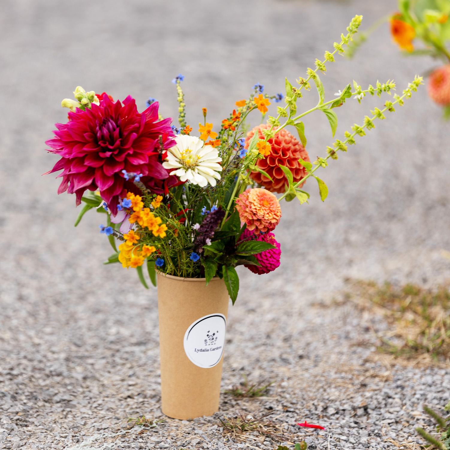 A travel-size brown paper cup filled with flowers