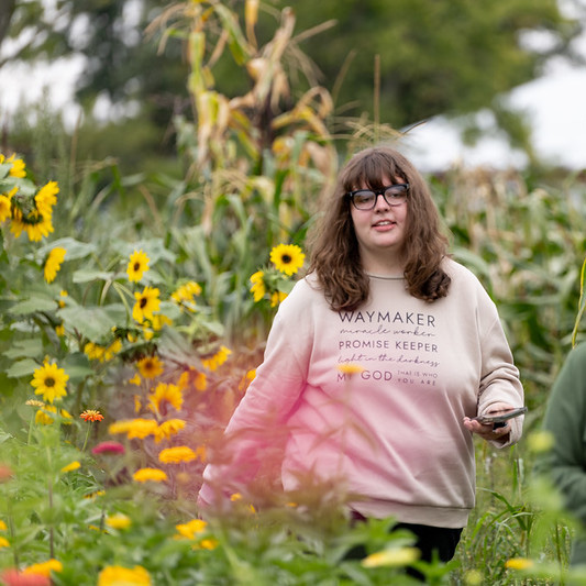A student walking through rows of flowers on the farm