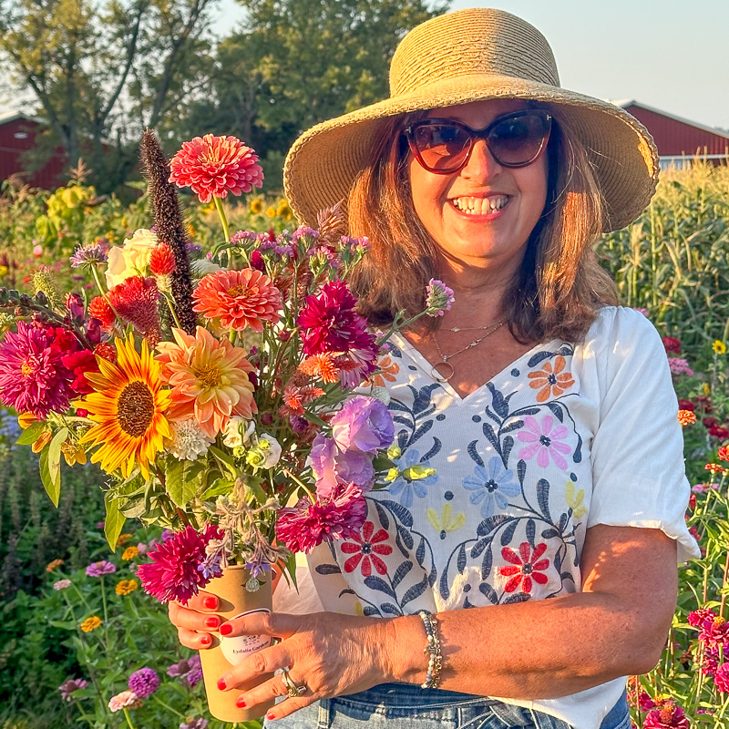 A woman in a sun hat holding her self-picked bouquet at golden hour
